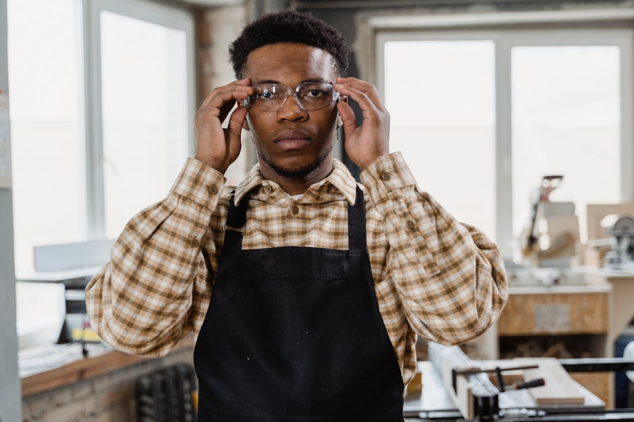 Professional woodworker in workshop wearing apron and glasses, focusing on craftsmanship.